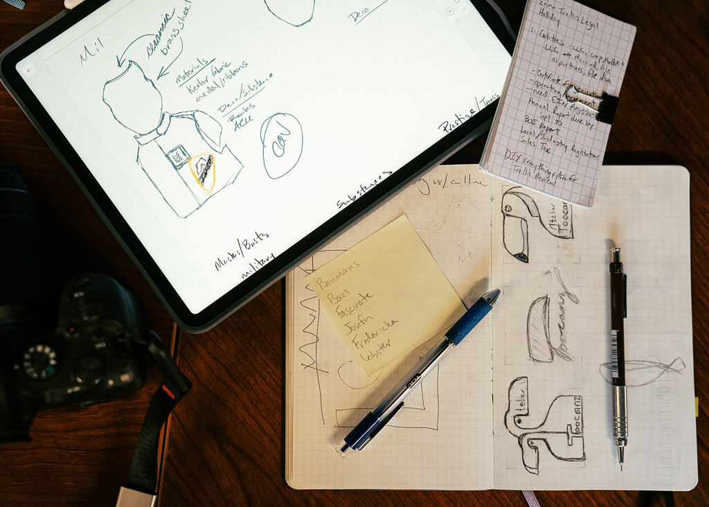 Image of sketch book with pens laying over, and an iPad with designs on the screen